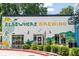 Exterior of Elsewhere Brewing featuring a white facade with green and yellow accents, landscaped bushes, and outdoor seating at 383 Pratt Se Dr # 503, Atlanta, GA 30315