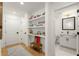 Hallway with wooden floors and open shelves containing photos, books and art, leading to powder room at 383 Pratt Se Dr # 503, Atlanta, GA 30315