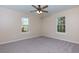 This bedroom has neutral walls, carpet flooring, a ceiling fan, and two windows providing natural light at 2775 Capri Dr, Cumming, GA 30041