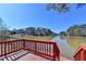 Stunning lake view from a red wooden deck surrounded by trees at 2382 Merrymount Dr, Suwanee, GA 30024