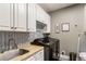 Laundry room featuring white cabinets, sink, modern black washer, and herringbone wallpaper at 3176 Crestmont Nw Way, Kennesaw, GA 30152