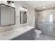 Bathroom featuring double sink vanity, framed mirrors, and walk-in shower with glass doors at 10104 Windrush Ln, Alpharetta, GA 30009