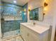 This bathroom boasts blue tile, glass shower doors, modern fixtures, and a white vanity with marble countertop at 6787 Hembree Dr, Austell, GA 30168