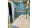 Modern bathroom featuring blue marbled tile, glass shower door, and white quartz vanity with gold hardware at 6787 Hembree Dr, Austell, GA 30168