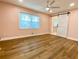 Bright bedroom featuring wood floors, light pink walls, a ceiling fan, and a white barn door at 6787 Hembree Dr, Austell, GA 30168
