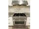 Close up of stainless steel stovetop and oven with modern backsplash and cabinetry at 6787 Hembree Dr, Austell, GA 30168