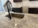 Close-up of the kitchen island featuring granite countertop, stainless steel sink, and modern faucet at 4371 Portsbrook Ave, Snellville, GA 30039