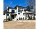 Modern white brick house featuring black framed windows, stone walkway, and manicured shrubbery under a bright blue sky at 4524 Mystic Dr, Sandy Springs, GA 30327
