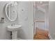 Clean bathroom featuring a pedestal sink, oval mirror, and tile floors with a glimpse of the staircase nearby at 1555 Mosaic Way # 1555, Smyrna, GA 30080