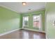 A green bedroom with hardwood floors, white trim, and two windows with curtains at 1555 Mosaic Way # 1555, Smyrna, GA 30080