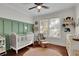 Charming Bedroom with a crib, accent wall, ceiling fan, hardwood floors, and sunlit windows at 265 Haas Se Ave, Atlanta, GA 30316