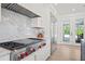Modern kitchen features stainless steel appliances, a marble backsplash, and white custom cabinetry at 840 Old Driver Road, Whitesburg, GA 30185