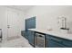 Functional laundry room featuring blue accent cabinetry with seating, storage, and a stylish tile backsplash at 840 Old Driver Road, Whitesburg, GA 30185
