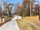 Modern home featuring a long driveway, fenced yard, and lush trees at 6178 Lake Lanier Heights Road, Buford, GA 30518