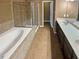 Well-lit bathroom featuring a soaking tub, glass shower, double vanity, and tile floors at 4954 Wyeth Way, Alpharetta, GA 30022