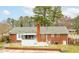 An exterior shot of a brick home featuring a screened-in porch, deck, and well-maintained yard at 3261 Hidden Forest Dr, Snellville, GA 30078