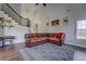 Spacious living room with a large sectional sofa, statement rug, and staircase at 20 Alison Trail, Covington, GA 30014