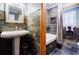 Bathroom with slate-tiled walls, a pedestal sink, soaking tub, and decorative mirror at 656 Gunby Se Rd, Marietta, GA 30067