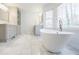 Bright bathroom featuring a luxurious soaking tub, marble floors, and a double vanity with natural light at 656 Gunby Se Rd, Marietta, GA 30067