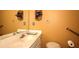 Cozy half bathroom with cream-colored vanity, mirror, and mustard colored walls, next to accessibility support bars at 1500 Elena Dr, Mcdonough, GA 30253