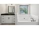 Bathroom features a soaking tub, vanity with black countertop and modern fixtures at 1511 New Hope Rd, Locust Grove, GA 30248