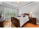 Bedroom with a ceiling fan, tray ceiling, hardwood floors, and large windows overlooking the yard at 308 Helena Pl, Mcdonough, GA 30252