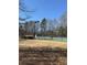Community tennis courts surrounded by a fence line, trees, and a grassy lawn on a sunny day at 3331 Freedom Nw Lndg, Kennesaw, GA 30144