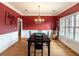 Well-lit dining room with red walls, wood floors, chandelier, and large windows providing ample light at 1213 Fairwinds Dr, Loganville, GA 30052