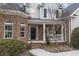 Charming brick home entrance with a cozy front porch, classic black door and manicured landscaping at 1213 Fairwinds Dr, Loganville, GA 30052