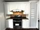 Gourmet kitchen area featuring modern stainless steel oven and range with custom white cabinets, and tiled backsplash at 1298 Belmont Se Ave, Smyrna, GA 30080