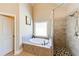 Bathroom with a walk-in shower, soaking tub with tile surround and a large window at 6055 Climbing Rose Way, Cumming, GA 30041