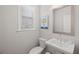 Stylish powder room featuring a pedestal sink, modern fixtures, and a decorative painting, all illuminated by natural light at 1336 Rosen Rd, Brookhaven, GA 30319