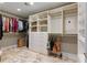 Spacious walk-in closet with custom built-in shelving, drawers, hanging rods, and unique travertine tile flooring at 6715 Brookline Ct, Cumming, GA 30040