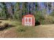 Close-up of a red and white storage shed in a grassy backyard setting at 6582 Malvin Dr, Mableton, GA 30168