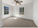Bright bedroom featuring plush carpet, two large windows, and a ceiling fan with light fixture at 8072 Crystal Ln, Douglasville, GA 30134