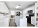 Bright kitchen featuring white cabinets, an island, black appliances, tiled floors, and access to the living room at 225 Stonewood Ct, Temple, GA 30179