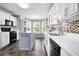 Modern kitchen with white cabinets, an island, mosaic backsplash, stainless steel appliances, and tiled floor at 225 Stonewood Ct, Temple, GA 30179