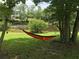 Scenic backyard view of an orange and black hammock suspended between trees with a serene lake backdrop at 2948 Legion Lake Rd, Douglasville, GA 30135