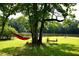 Backyard with a wooden swing and a disc swing hanging from a mature tree overlooking the calm waters of a lake at 2948 Legion Lake Rd, Douglasville, GA 30135
