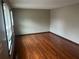 An empty bedroom featuring hardwood floors and a window with closed blinds for privacy at 5790 Northspring Dr, Ellenwood, GA 30294