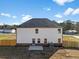 A two-story house featuring white siding, a dark roof, a small patio, and a wooden fence enclosing the backyard at 1599 Sungrown Way, Mcdonough, GA 30253
