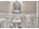 Clean bathroom featuring white tile, pedestal sink, arched mirror and modern hardware at 300 Peachtree Ne St # 6H, Atlanta, GA 30308