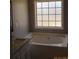 Bright bathroom featuring tub, window, and granite vanity at 561 Old Loganville Rd, Loganville, GA 30052