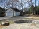 A detached garage with white siding, a black roof, and additional parking space on the paved driveway at 561 Old Loganville Rd, Loganville, GA 30052