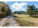 Wide shot of the property showing the dirt driveway and the home with large front yard at 1515 Ozora Rd, Loganville, GA 30052