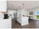 Modern white kitchen with an island, stainless steel appliances, and wood-look flooring at 718 Ocmulgee Crossing, Locust Grove, GA 30248