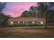 Ranch style home with a long porch and mature trees at twilight at 12142 Panhandle Rd, Hampton, GA 30228