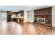 Open living room with a brick fireplace, wood floors, and connection to the kitchen at 12142 Panhandle Rd, Hampton, GA 30228