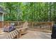 Inviting back deck with an adirondack chair and a wicker chair, looking out onto lush trees at 90 Lakeside Dr, Hiram, GA 30141