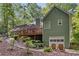 Rear exterior of the house with green siding, a deck, a one car garage, and mature landscaping at 90 Lakeside Dr, Hiram, GA 30141